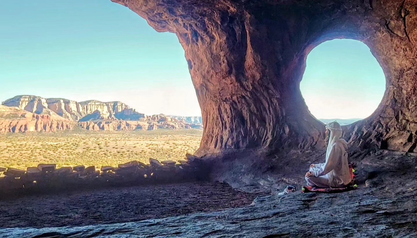 Hunter in meditation inside a desert sandstone arch overlooking the canyon.
