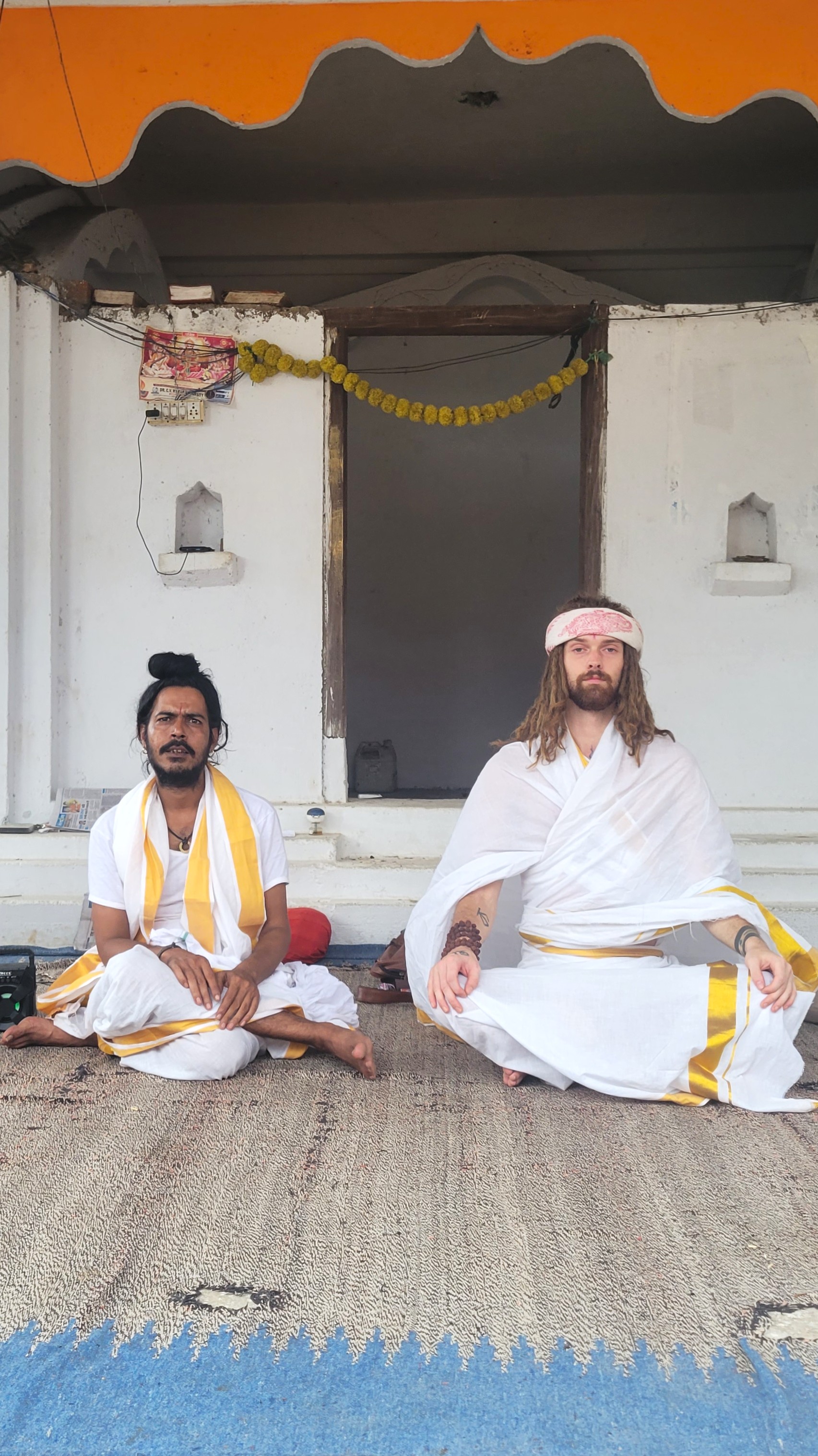 Hunter and his guru Baba Muni in white robes, meditating side by side before a temple shrine in Penukonda, India.